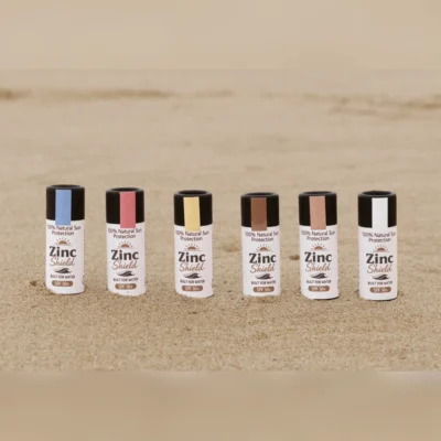 ZincShield SPF 50 mineral sunscreen sticks in multiple colours on beach sand