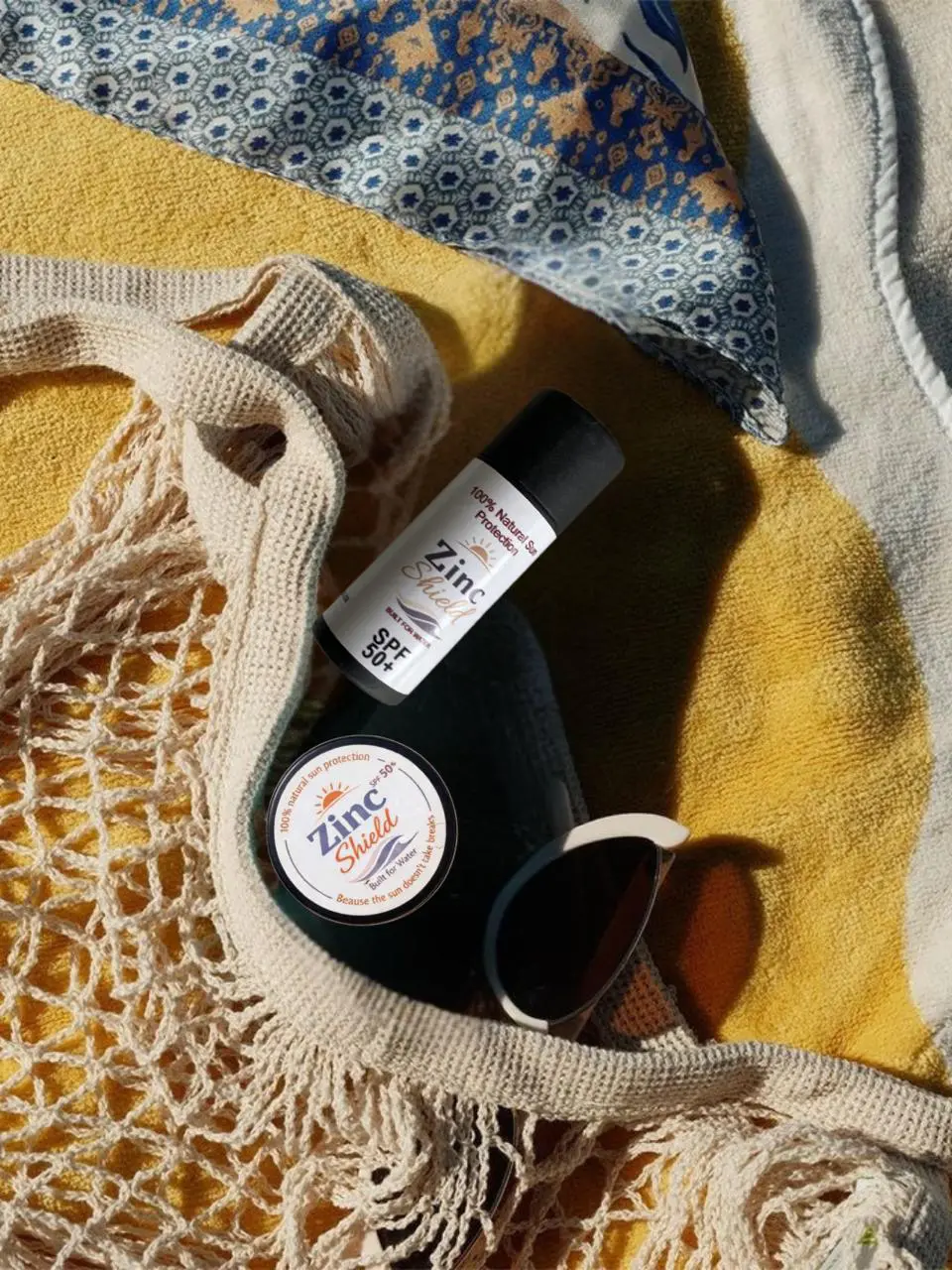Zinc Shield natural sunscreen in beach bag with summer essentials - must-have mineral sun protection
